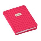 Es steht "Quo Vadis" auf einem kleinen Etikett. Rosa Notizbuch mit strukturiertem geometrischem Muster auf dem Einband.