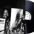 „Hank Mobley and his All Stars“ steht groß auf einer Aufnahme. Ein Mann hält Notenblätter, daneben eine Schallplatte.