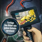 Eine Illustration zeigt eine Hand, die ein Gerät hält. Auf dem Bildschirm: Goldbarren, Münzen, Geldstapel. Text: "Farbige live Bilder aus jedem Geheimversteck!".