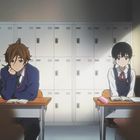 Zwei Schüler sitzen in einem Klassenzimmer an Schreibtischen, vertieft in Hefte, mit Schließfächern im Hintergrund.