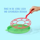 "RINGE IN DIE SCHALE LEGEN UND SEIFENBLASEN ERZEUGEN" - Eine Hand hält einen roten Blasenring über einer grünen Schale.