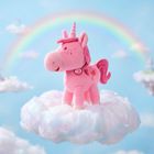 Ein rosa Plüsch-Einhorn mit Halsband steht auf einer Wolke, dahinter ein Regenbogen im blauen Himmel.