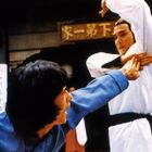 Oben sind chinesische Schriftzeichen. Zwei Männer in Kampfpose, einer in Blau, der andere in Weiß mit schwarzem Gürtel.