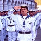 Eine Reihe von Matrosen in weißen Uniformen mit Mützen, auf denen "H.K. WATER POLICE" steht, ein Matrose grüßt.