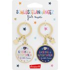 „SCHLÜSSELANHÄNGER für zwei“, „KACKTAGE IN GLITZER TUNKEN & funkeln lassen“. Zwei runde goldene Schlüsselanhänger.