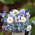 April 2027 Kalender, "Liebe und Freundschaft..." Text. Blumen und Herzdeko in einem Metallkrug, pastellfarbene Töne.