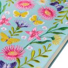 Blumen- und Schmetterlingsstickerei auf hellblauem Hintergrund, mit gelben Schmetterlingen und rosa, lila Blumen.