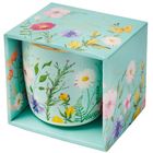 Text: "Das Leben ist schön". Eine teal-farbene Box und Tasse mit bunten Blumen und Schmetterlingen, dekorativ gestaltet.