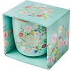 Text: "Kleine Auszeit". Eine Tasse in blauer Verpackung mit bunten Blumenmotiven.
