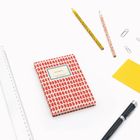 "NOTIZBUCH" steht auf einem roten Heft. Drumherum: zwei Bleistifte, ein Lineal, Büroklammern, ein gelbes Papierstück.