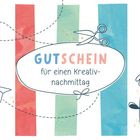 "Gutschein für einen Kreativnachmittag" steht auf einem weißen ovalen Schild. Bunte Streifen, Schere, Papierflieger, Blume.