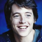 Es gibt keinen Text zu beschreiben. Ein lächelnder Mann vor blauem Hintergrund, trägt eine dunkelblaue Kapuzenjacke.