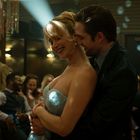 Es gibt keinen Text zu erwähnen. Eine Frau schaut über die Schulter, spärlich beleuchtet mit einem Spiegel im Hintergrund.