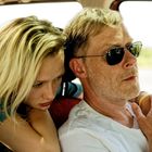 Zwei Menschen in einem Auto, sichtbar nah beieinander. Eine Person trägt eine Sonnenbrille.