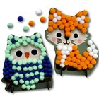 Zwei niedliche Figuren aus Pompoms: eine Eule mit Blau- und Grüntönen und ein Fuchs in Orange und Weiß.