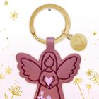 "Ich beschütze dich." zeigt einen rosa Schlüsselanhänger in Engel-Form mit floralen Details und goldenen Akzenten.