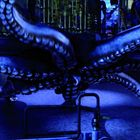 Ein riesiger Oktopus mit ausgebreiteten Tentakeln in einem industriellen, blau beleuchteten Raum voller Rohre und Maschinen.