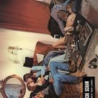 Der Text lautet: "FALSCHE SCHAM - Gefahren der Liebe". Menschen sitzen auf einem Sofa in einer gemütlichen, rustikalen Umgebung.