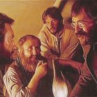 Vier Männer sitzen um eine Lampe, ihre Gesichter sind ernst und konzentriert.