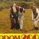 Der Text "SODOM 2000" steht in kräftiger Schrift. Drei Personen stehen auf einer Wiese, eine Frau in schwarzer Kleidung.