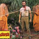 „Luana“ steht in einem gelben Kasten. Ein Mann in beiger Kleidung umgeben von Menschen in orangenen Gewändern und Pflanzen.