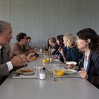 Zwei Personen in einem Speisesaal sitzen sich an einem Tisch gegenüber und unterhalten sich.