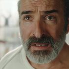 Ein Mann mit dichtem Bart und ernstem Gesichtsausdruck, vor einem unscharfen Hintergrund.