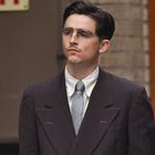 Jemand in einem Anzug, mit einem Schild im Hintergrund, auf dem "EXIT" steht. 