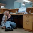Tasse: „THIS MIGHT BE WINE.” Zwei Frauen verstecken sich erschrocken unter einem Büro-Schreibtisch mit Computer und Lampe.