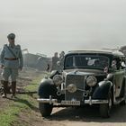 Ein Auto mit Nummernschild „IA-134431“, daneben ein Mann in Uniform, umgeben von alten Fahrzeugen und Soldaten.