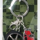 Text: "BRUNNEN" und "www.brunnen.com". Ein Schlüsselanhänger mit Autoreifen und rotem Auto, verpackt vor karierter Kulisse.