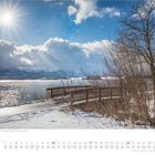 "Hopfen am See, Bayern, Deutschland" unten. Ein verschneiter Steg führt über einen See, strahlende Sonne am Himmel.
