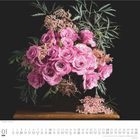 01, DUMONT. Ein Blumenarrangement mit rosa Rosen und grünen Blättern auf dunklem Hintergrund.