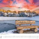 Text: „Lieblingsplatzl“ auf einer Holzbank. Schneebedeckte Berge im Hintergrund, darunter ein gefrorener See bei Sonnenuntergang.