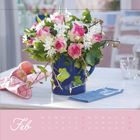 Februar-Kalender mit Blumenstrauß in blauer Vase. Tisch mit Äpfeln und Stoffservietten.