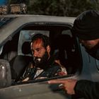 Ein Mann mit blutiger Stirn sitzt erschöpft in einem SUV. Ein anderer Mann zeigt auf ihn durch das offene Fenster.