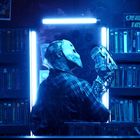 "CREATURE EATS". Eine maskierte Figur, blaues Licht, von VHS-Kassetten umgeben. Eine mysteriöse, intensive Stimmung.