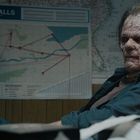 Text: "CAMPER FALLS." Eine grobe Landkarte mit roten Linien. Eine Person mit stark vernarbtem Gesicht sitzt im Raum.