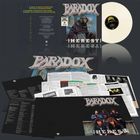 "Paradox" und "Heresy" auf einem Albumcover, Abbildung eines Mönchs, Schallplatte, und Bandfotos.