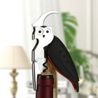 Kein Text. Ein Korkenzieher in Eulenform, sitzt auf einer Weinflasche. Im Hintergrund eine Lampe und Pflanze.
