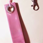 Ein pinkfarbener Schlüsselanhänger mit Metallring und Karabinerhaken, liegend auf einem hellen Untergrund.