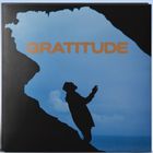 Text: "GRATITUDE". Silhouette einer Person zwischen Felsformationen im Hintergrund eines blauen Himmels.