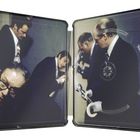 Männer in Anzügen arbeiten konzentriert in einem Raum. Sie halten Werkzeuge und inspizieren etwas an der Wand.