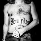"Born t'Lose" ist auf dem Bauch einer Person tätowiert. Darunter ist ein Tattoo einer sich selbst beißenden Schlange.