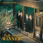 "GRANDMAS HOUSE" und "Baby You're a WINNER!" sind in kräftigem Gelb. Drei Personen in Anzügen stehen hinter einer Glastür.