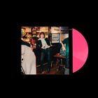 Es gibt keinen lesbaren Text. Ein Mann lehnt an einer Bar, mit einem Getränk in der Hand. Daneben eine pinke Schallplatte.