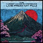 "The Yussef Dayes Experience Live from Mt Fuji." Illustration eines Berges mit schneebedecktem Gipfel, roter Sonne und Bäumen.
