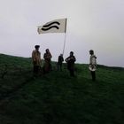 Fünf Menschen auf einer Wiese mit einem Banner, das zwei geschwungene schwarze Linien zeigt.