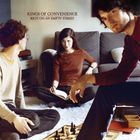 "KINGS OF CONVENIENCE - RIOT ON AN EMPTY STREET." Drei Personen im Wohnzimmer, Frau liest, Männer spielen Schach.