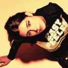 Der Text "EASY PEELER" steht auf einem dunklen Oberteil. Eine Person blickt intensiv in die Kamera, in warmen Gelbtönen.